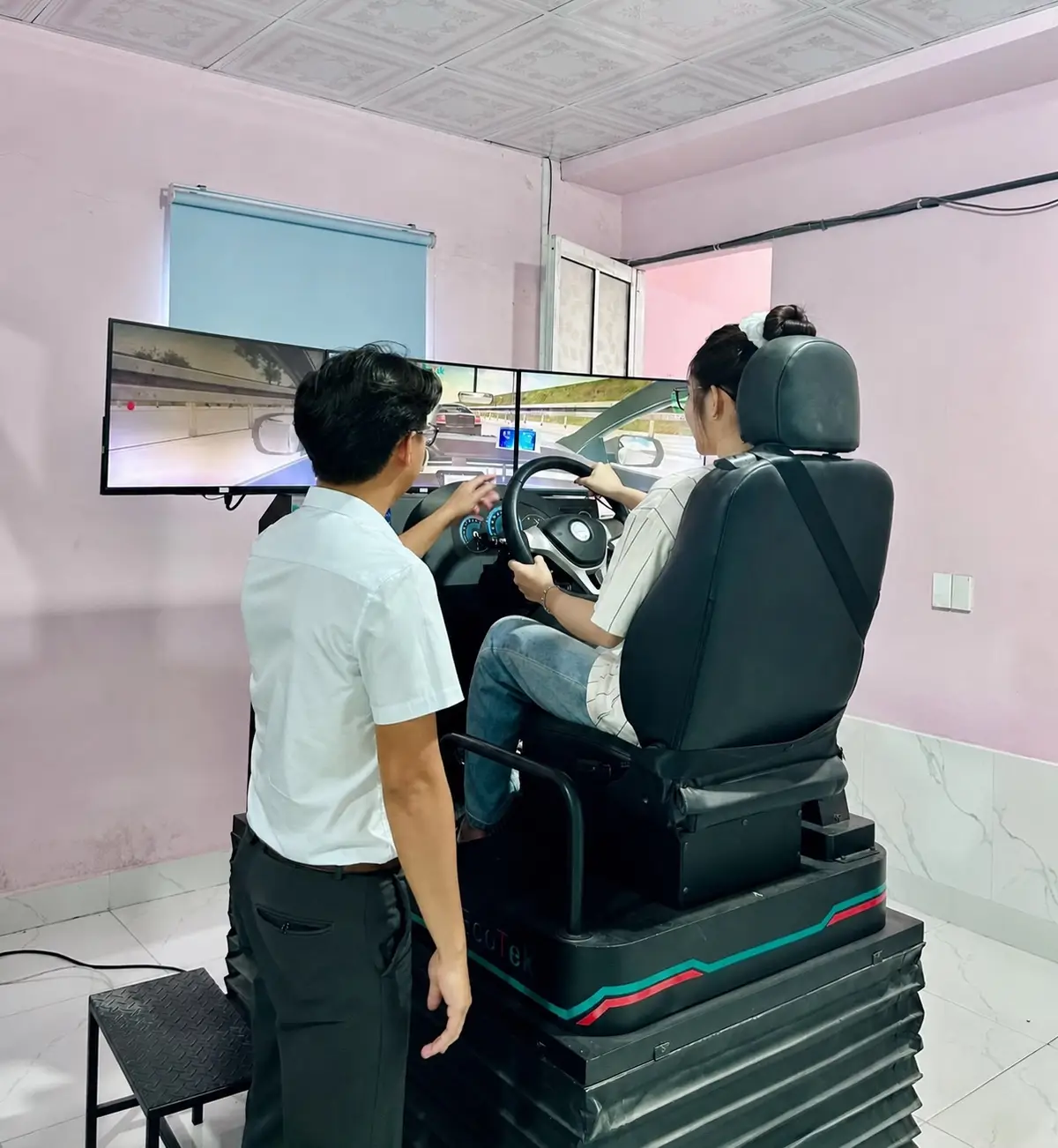 Giáo viên hướng dẫn học viên thực hành lái xe trên cabin